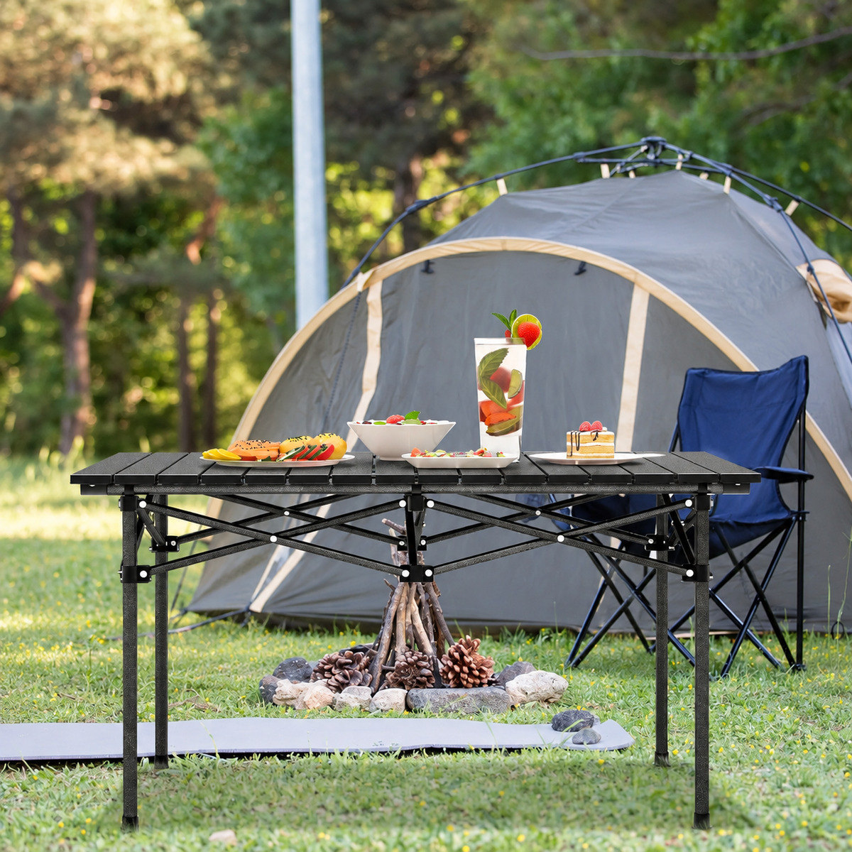 Klappbarer Campingtisch mit Aluminium-Rollplatte vor einem Zelt auf dem Campingplatz, gedeckt mit Speisen und Getränken